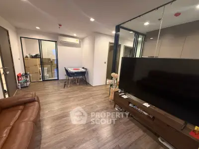 Spacious modern living room with sleek wooden flooring and large TV setup.