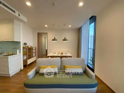 Modern open-plan living room with cozy sofa and dining area, featuring large windows and stylish lighting.