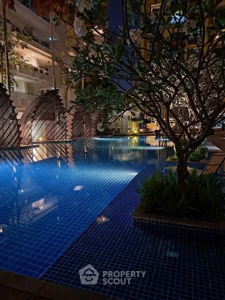 Luxurious night view of a modern apartment pool with ambient lighting and lush greenery.