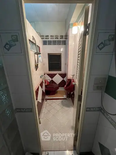 Charming vintage bathroom with unique red fixtures and tiled walls, perfect for a retro-inspired home.