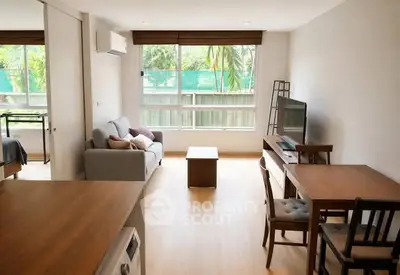 Modern living room with natural light, wooden flooring, and cozy furniture in a stylish apartment.
