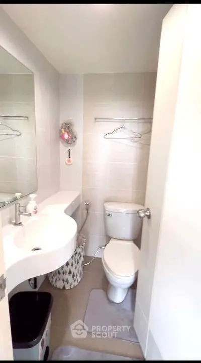 Modern bathroom with sleek fixtures and neutral tiles, featuring a compact layout and contemporary design.