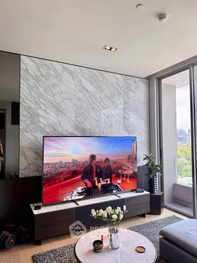 Luxurious living room with marble accent wall and large TV, offering a stunning city view.
