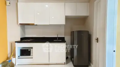 Modern kitchen with sleek white cabinets and compact fridge in a cozy apartment.