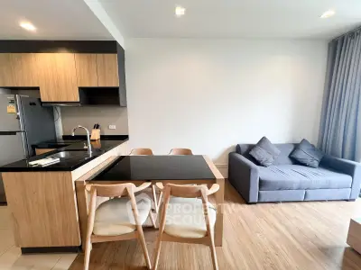 Modern open-plan kitchen and living room with stylish wooden furniture and cozy sofa.