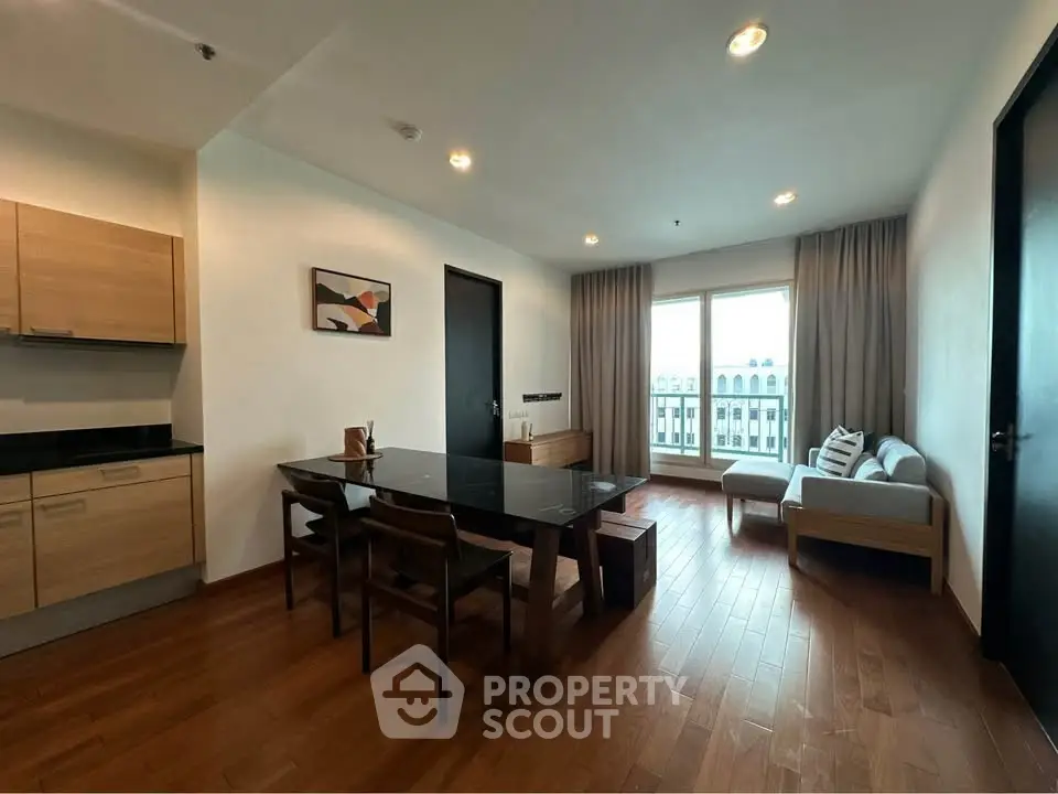 Modern living room with wooden flooring and stylish furniture, featuring a large window with a city view.