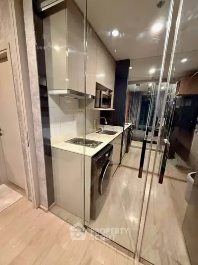 Modern compact kitchen with glass partitions and built-in appliances in a stylish apartment.