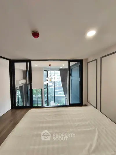 Modern bedroom with large windows and balcony view in urban apartment