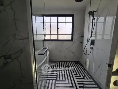 Modern bathroom with marble walls and geometric floor tiles, featuring a sleek shower area.