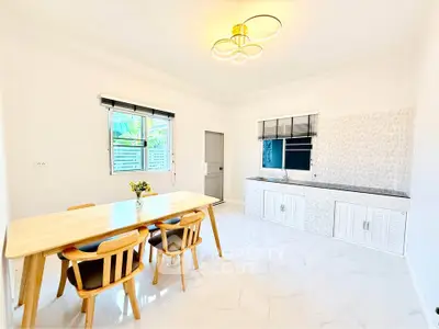 Bright and modern kitchen with dining area, featuring sleek white cabinets and elegant lighting.