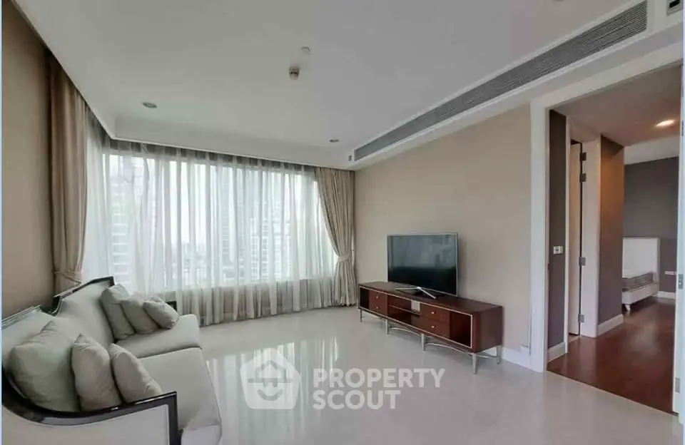 Spacious modern living room with large window and sleek furniture in luxury apartment.