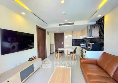 Modern living room with open kitchen, leather sofa, and wall-mounted TV in a stylish apartment.