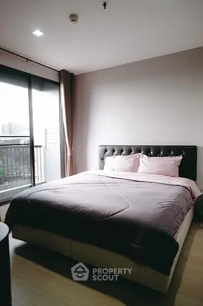 Spacious bedroom with large bed and balcony view in modern apartment