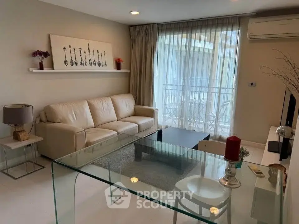 Modern living room with glass table and cozy sofa, featuring elegant decor and natural light.