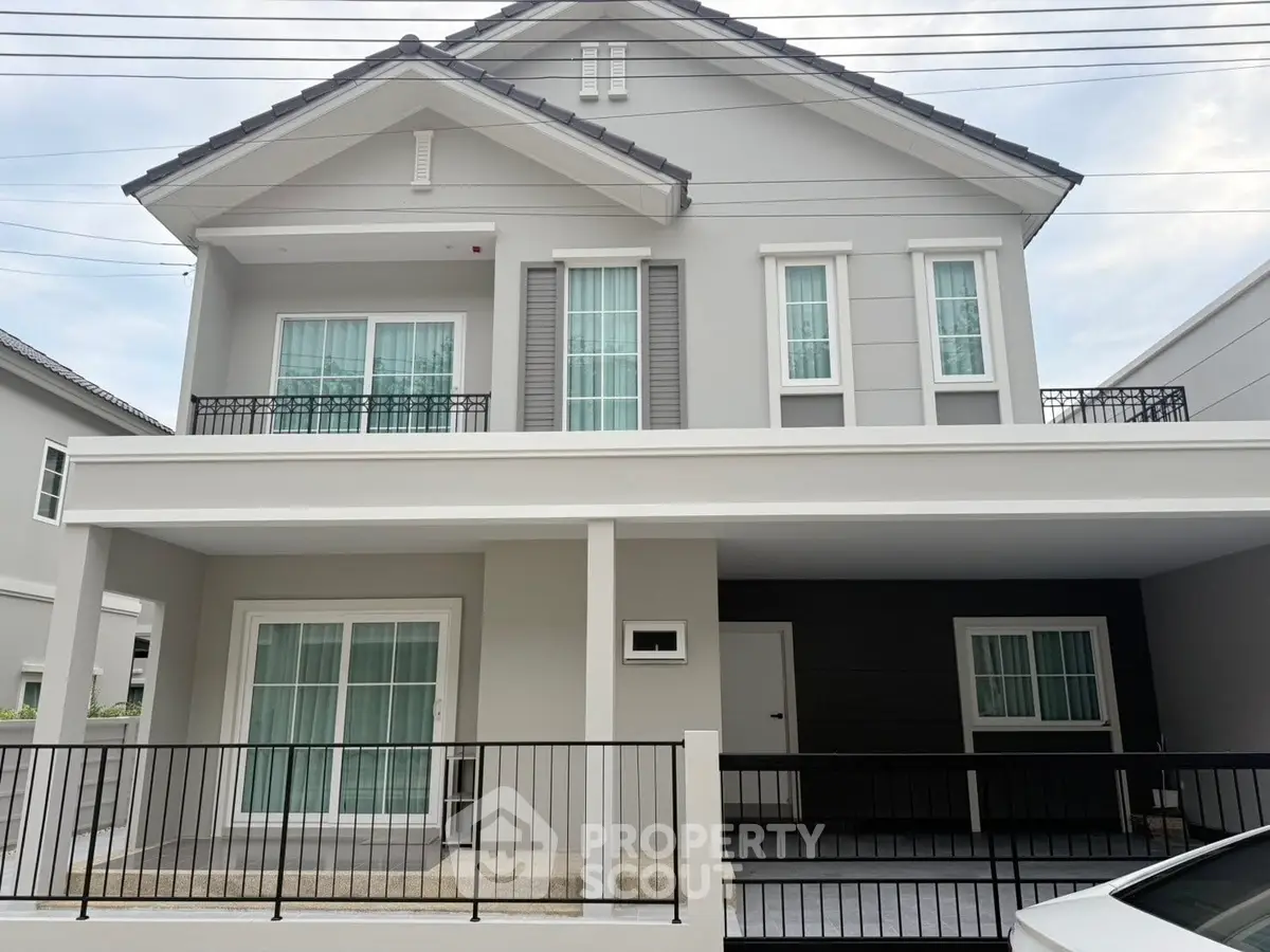 Modern two-story house with elegant facade and balcony in suburban neighborhood.
