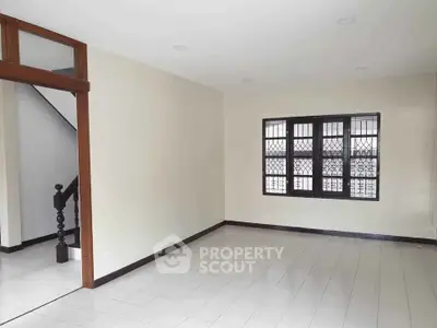 Spacious living room with tiled flooring and large window in a modern home.