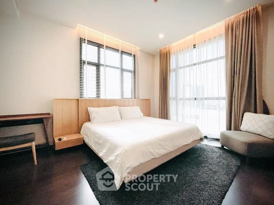 Spacious modern bedroom with large windows and elegant decor in a luxury apartment.