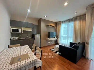 Modern living room with open kitchen and dining area, featuring stylish furniture and natural light.