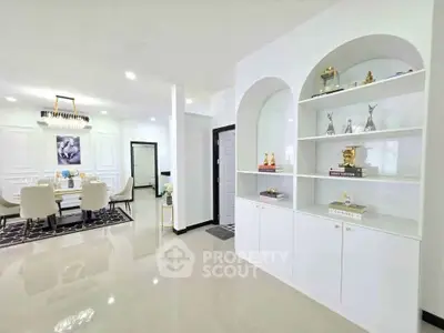 Elegant open-plan living and dining area with modern decor and built-in shelving.