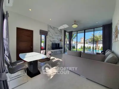 Modern living room with elegant decor and pool view, featuring sleek furniture and large windows.