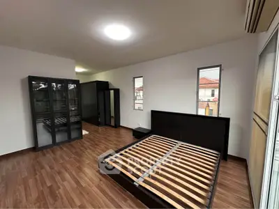 Spacious bedroom with wooden flooring and modern furniture, featuring large windows for natural light.