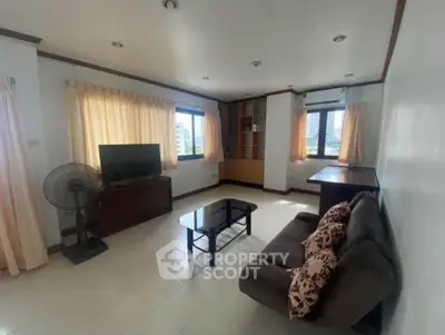 Spacious living room with modern decor and large windows offering city views.