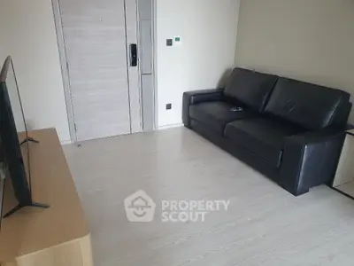 Modern living room with sleek black leather sofa and flat-screen TV.