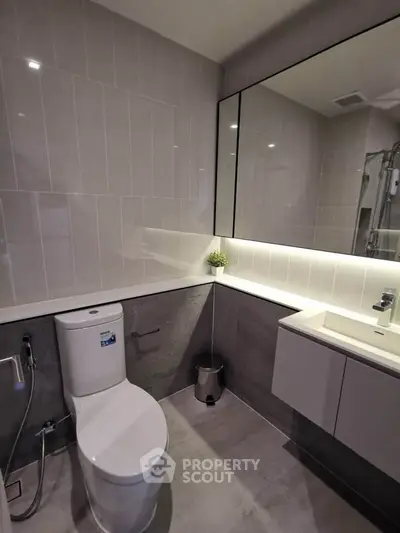 Modern bathroom with sleek design, featuring a large mirror and contemporary fixtures.