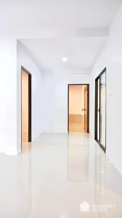 Spacious modern hallway with glossy floors and multiple doorways in a minimalist apartment.