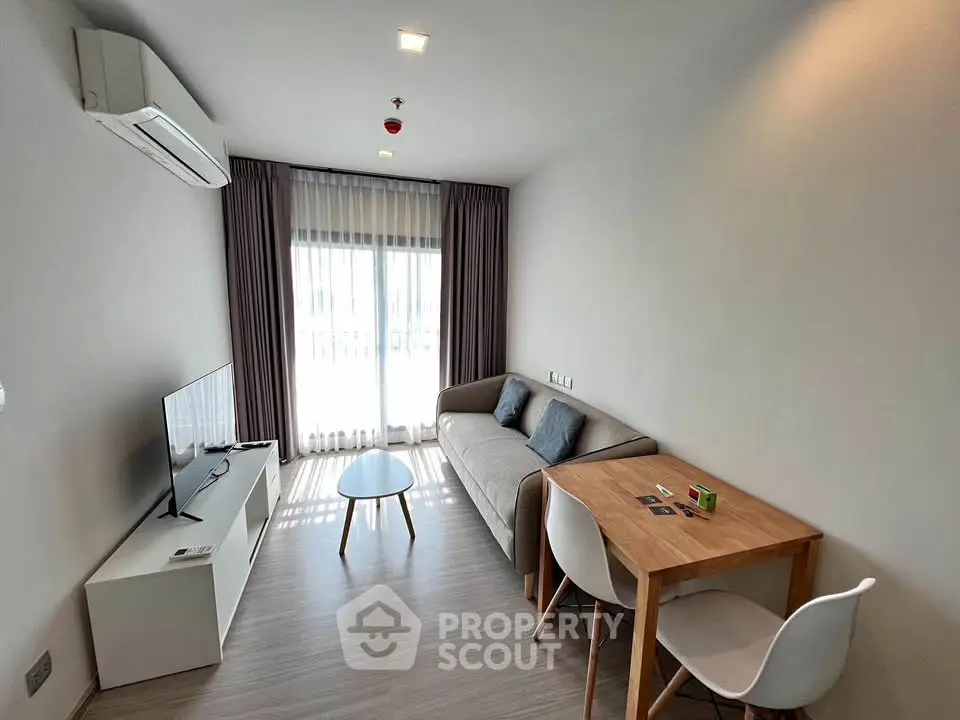 Modern living room with natural light, featuring a cozy sofa, TV, and dining table in a stylish apartment.