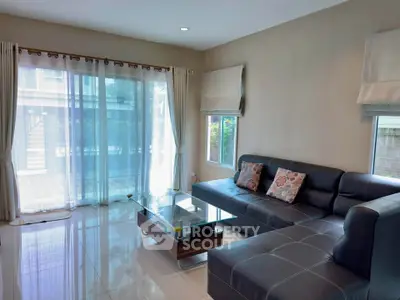 Spacious living room with modern leather sofa and large windows offering natural light.