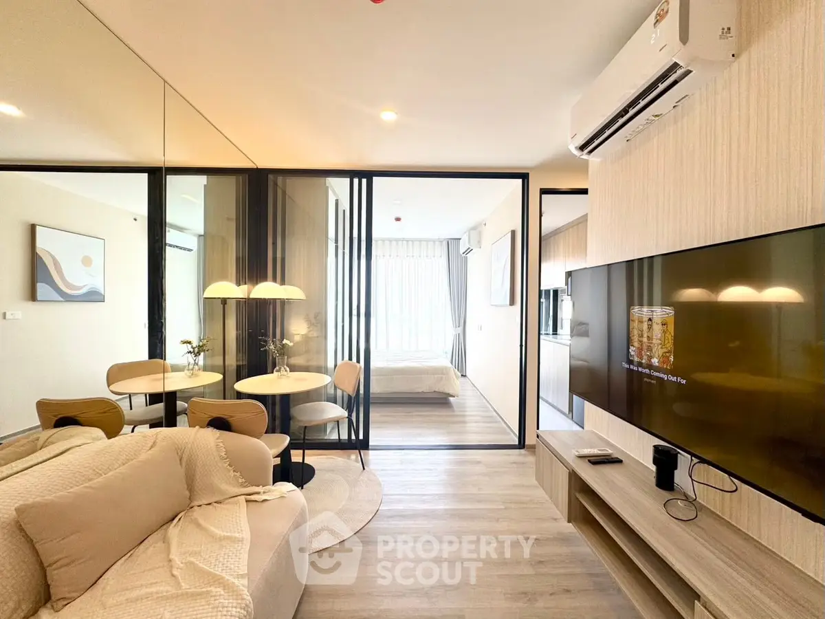 Modern open-plan living room with stylish decor and glass partition leading to bedroom