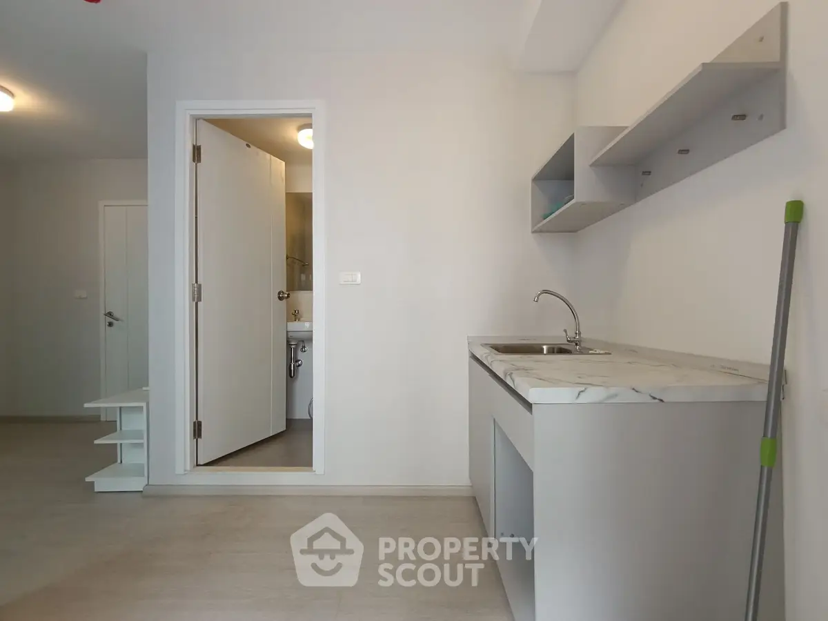 Modern minimalist kitchen with marble countertop and open shelving in a bright apartment.