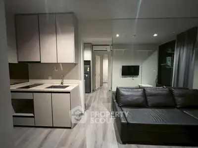 Modern open-plan living room with sleek kitchen and stylish black leather sofa.
