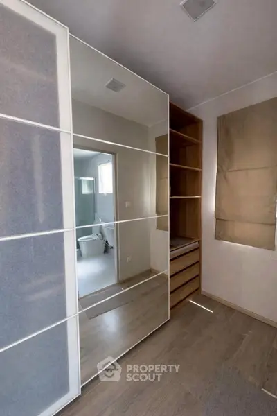 Modern bedroom with sleek wardrobe and view into stylish bathroom