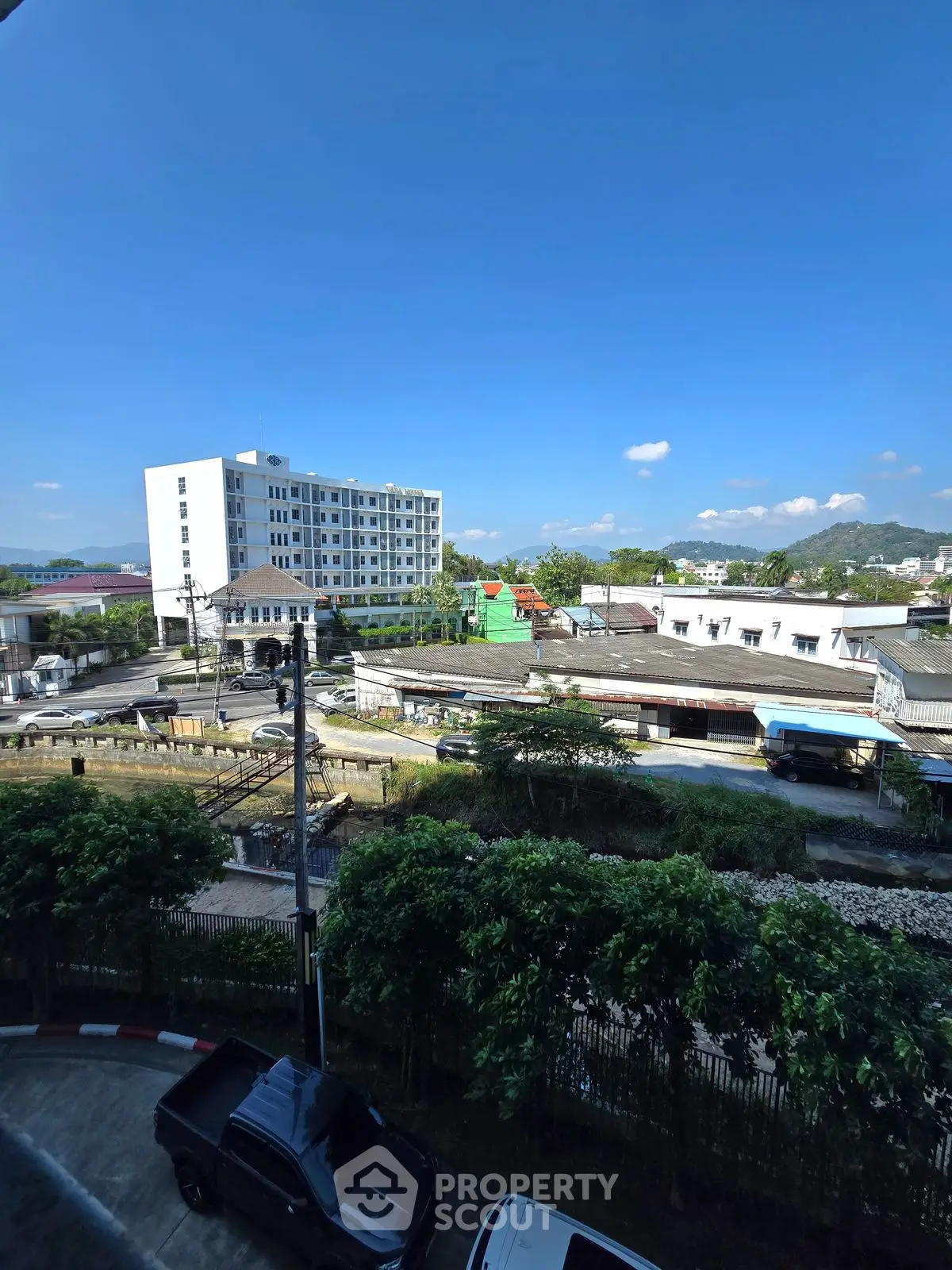 Stunning urban view with modern building and lush greenery under clear blue sky.