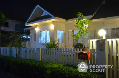 Charming suburban home with white picket fence and warm evening lighting