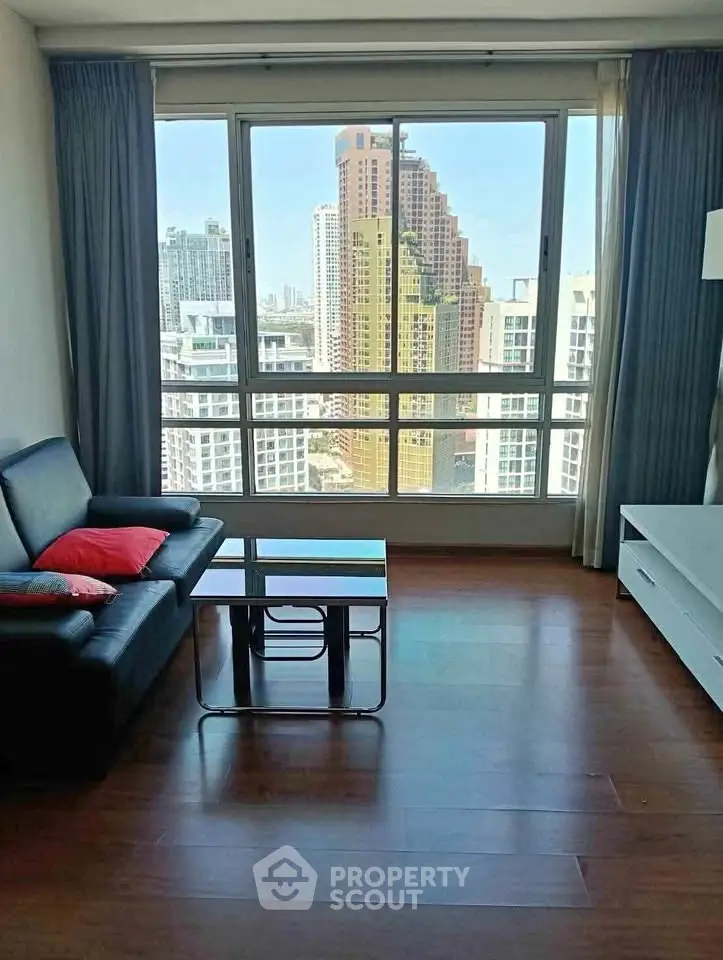Modern living room with city view, featuring sleek furniture and large windows.