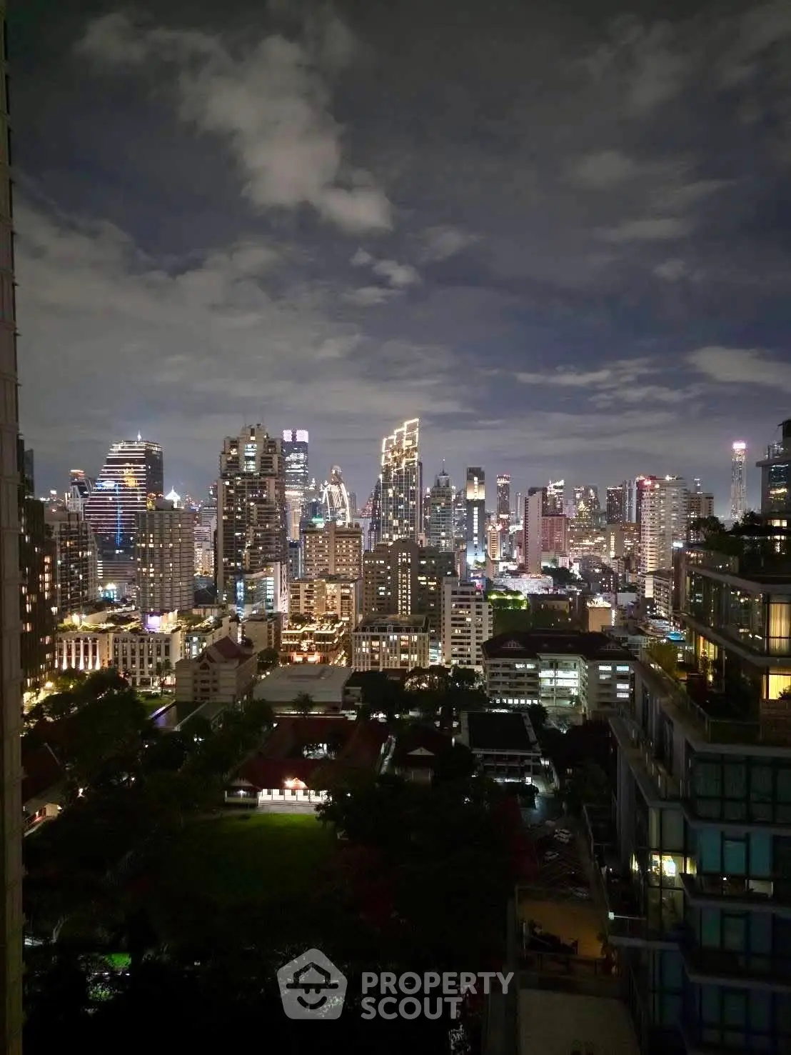 Stunning city skyline view from a high-rise balcony at night, showcasing vibrant urban lights and modern architecture.