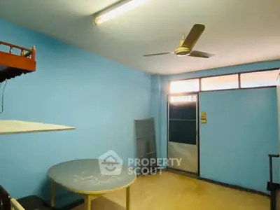 Cozy room with blue walls, ceiling fan, and round table, ideal for versatile use.