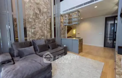 Luxurious modern living room with plush gray sofa and elegant marble accents.
