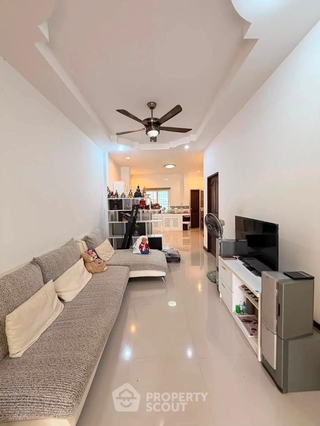 Spacious living room with modern decor and ceiling fan, perfect for relaxation and entertainment.