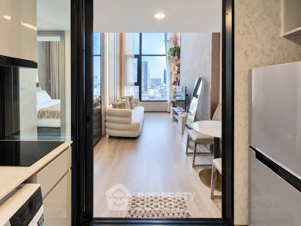Modern apartment interior with open kitchen and cozy living room featuring large windows and city view.