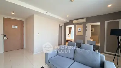 Modern living room with gray sofa and dining area in open layout apartment.