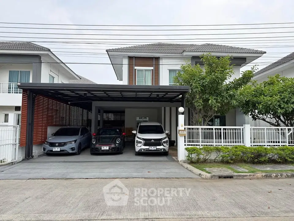 Modern two-story house with spacious driveway and carport, featuring contemporary design and lush greenery.