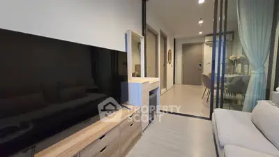 Modern living room with sleek TV setup and elegant dining area in open layout apartment.
