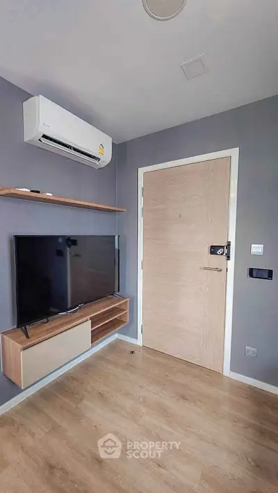 Modern living room with sleek TV setup and air conditioning in a stylish apartment.