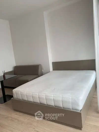 Modern bedroom with minimalist design featuring a cozy bed and stylish sofa, perfect for urban living.