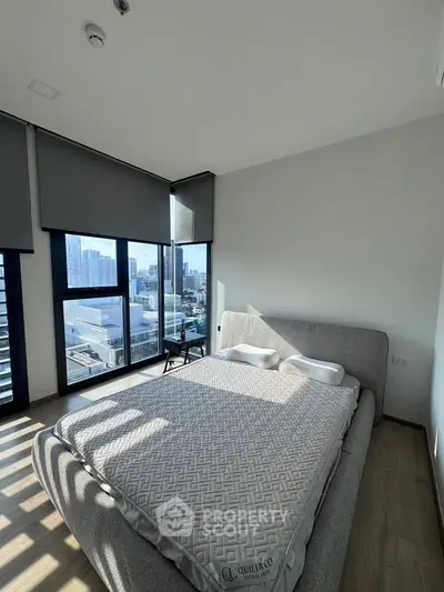 Spacious bedroom with large windows offering stunning city views and modern decor.