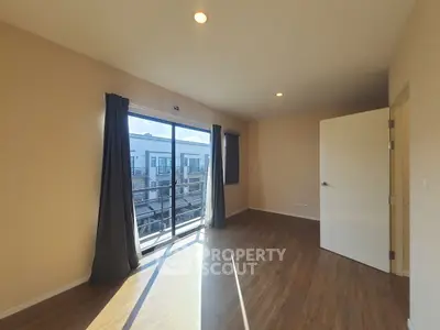 Spacious sunlit room with large window and wooden flooring, perfect for modern living.